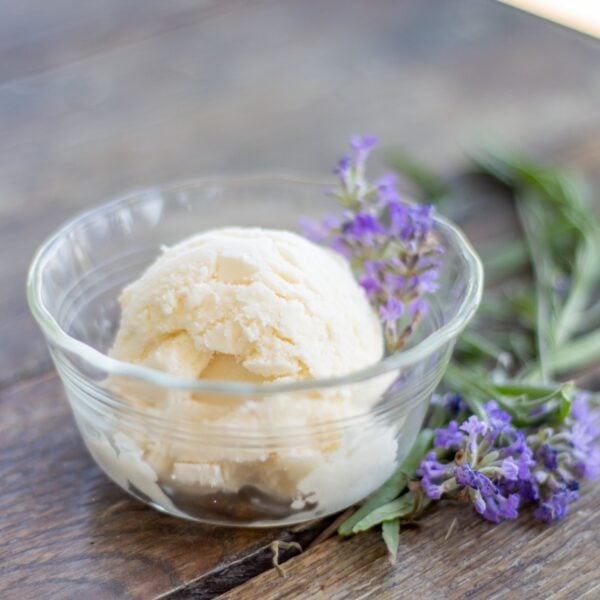 A scoop of ice cream in a dish sits next to lavender.