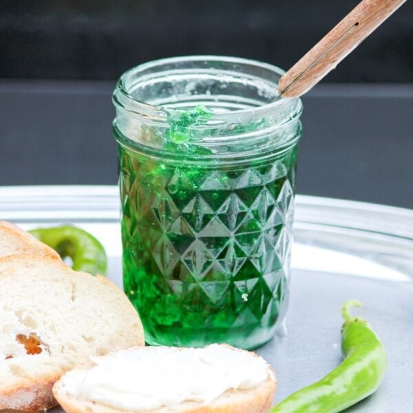 Green jelly fills a jar sitting on a platter.