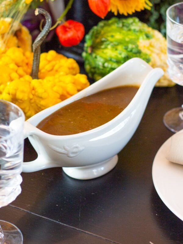 Gravy rests in a decorative dish on a table.