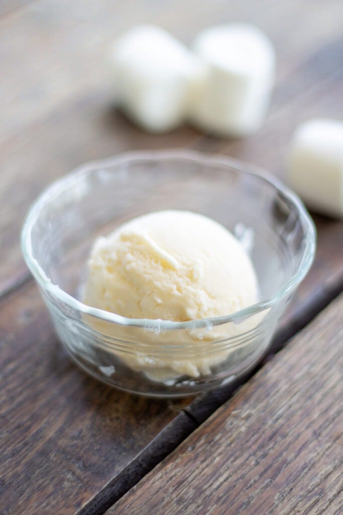 A scoop of marshmallow ice cream sits in a glass dish.