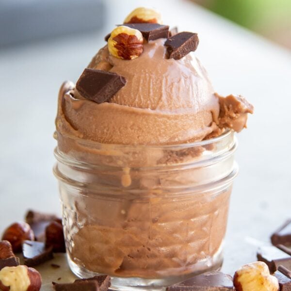A scoop of ice cream topped with hazelnut and chocolate sits in a dish.