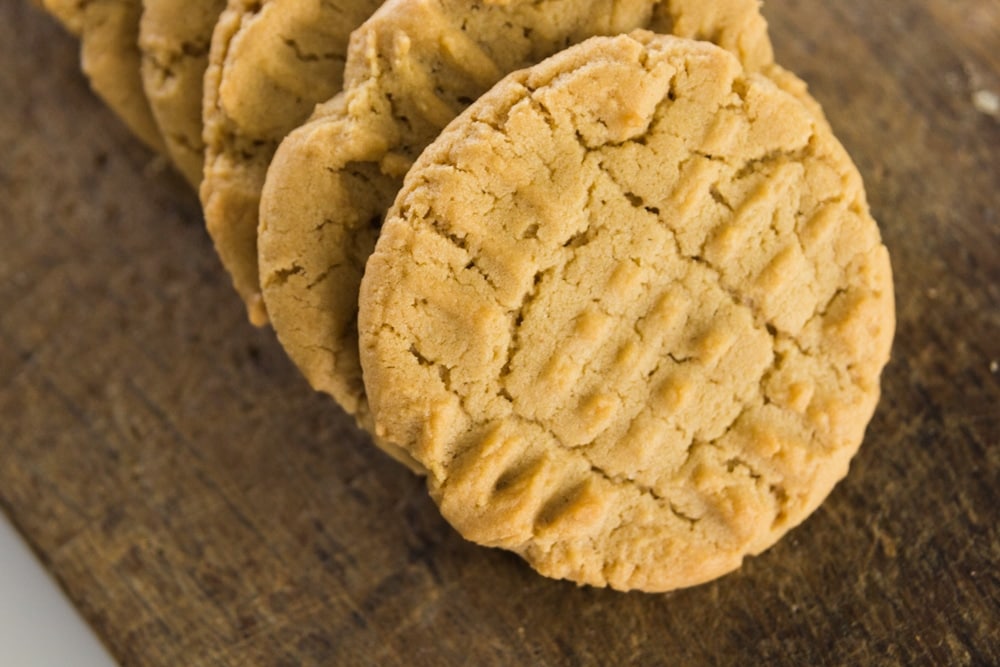 A cookie leans against other cookies on a wood block.