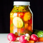 A jar full of pickled vegetables sits on a table.