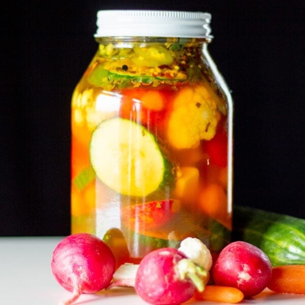 A jar full of pickled vegetables sits on a table.