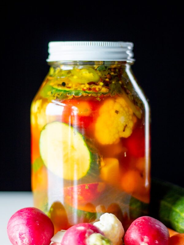A jar full of pickled vegetables sits on a table.