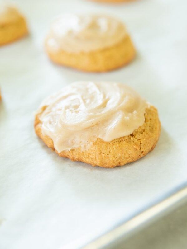 Cookies in a row sit on a parchment-lined pan.