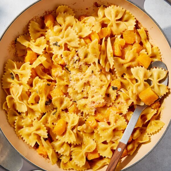 Large pot filled with cooked pasta and butternut squash with spoon resting against the side of the pot.