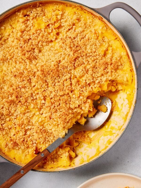 Large pot filled with baked butternut squash pasta with spoon resting in pot after scooping out a serving.