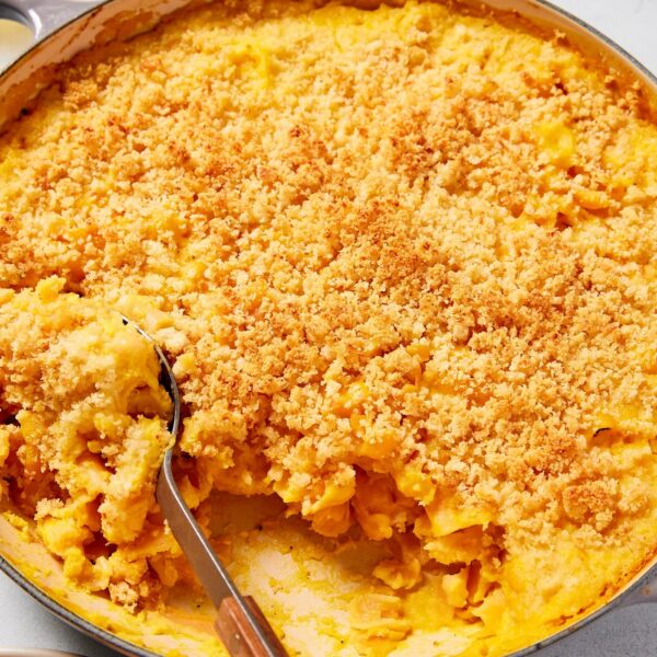 Large gray pot filled with cooked butternut squash pasta with spoon scooping out a serving of pasta.