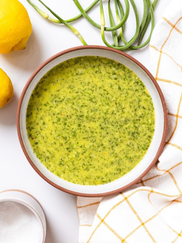 A bowl of chimichurri sauce on a table.