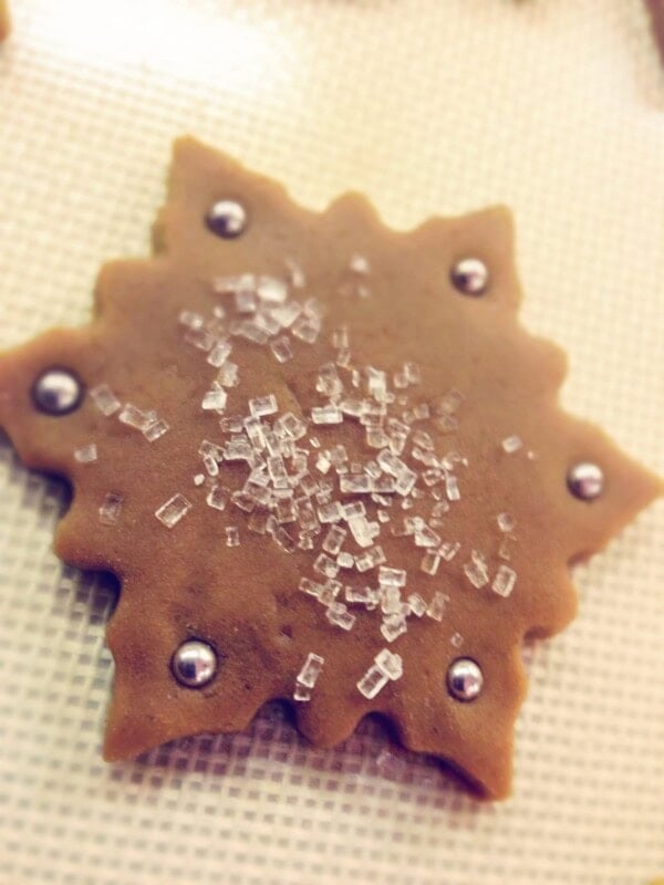 A gingerbread cookie rest on a baking mat.