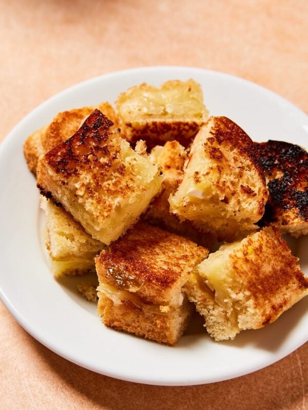 White plate filled with pile of grilled cheese croutons sliced into squares with crispy brown edges.