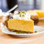A slice of pumpkin pie cheesecake sits on a plate.