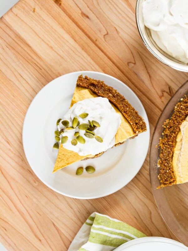 A slice of pumpkin pie cheesecake sits on a table.