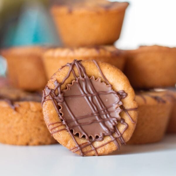 A cookie with a peanut butter cup sits propped up by a tower of cookies.