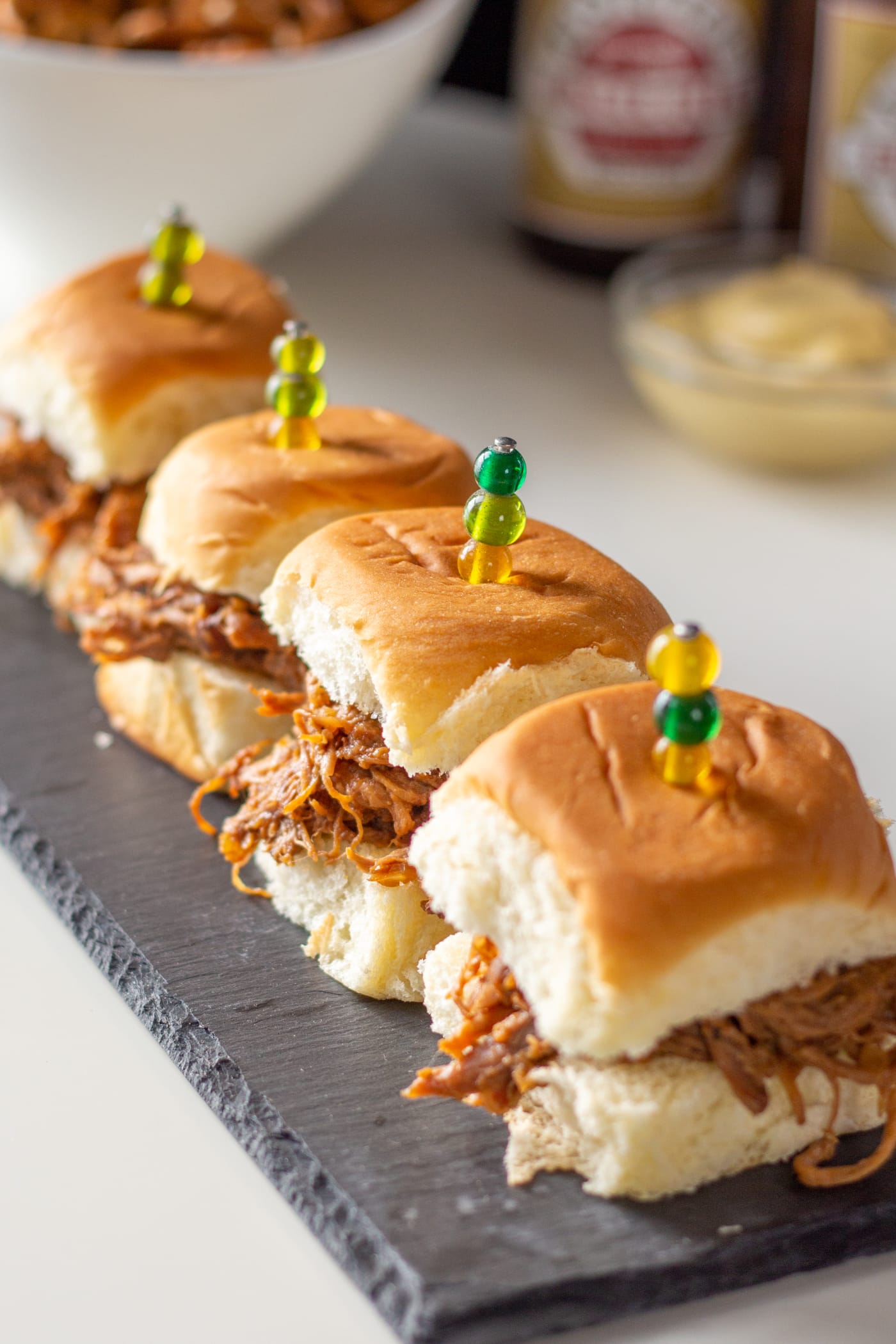 Pulled pork sliders sit on a serving stone.