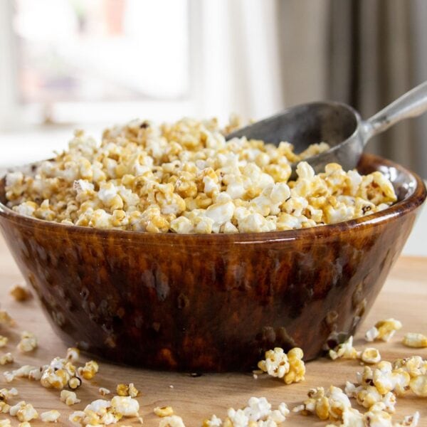 A bowl full of caramel corn and a scoop.