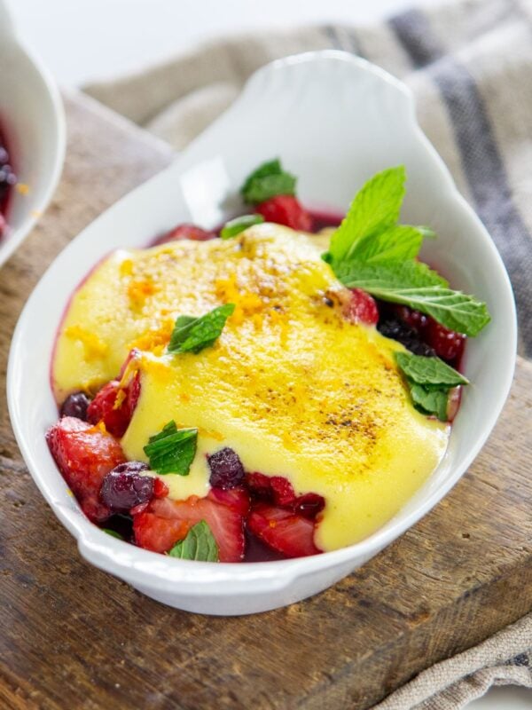 Berries topped with sabayon sit in a serving dish.