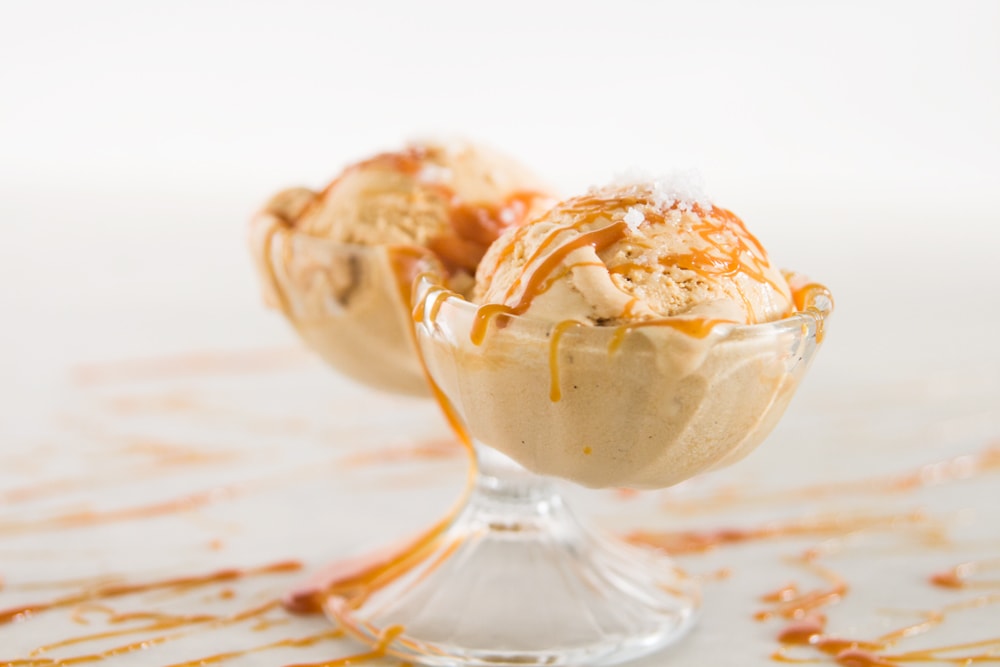 Two scoops of ice cream sit in a glass dish.