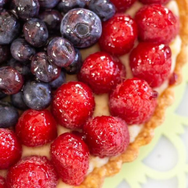 Blueberries and raspberries sit on top of a tart.
