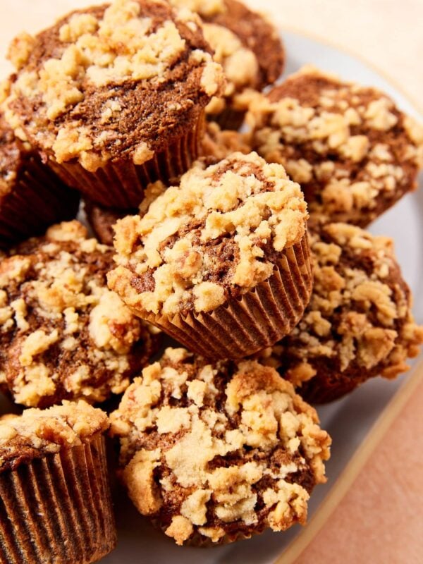 A pile of spiced carrot muffins with streusel topping sitting in a white bowl.