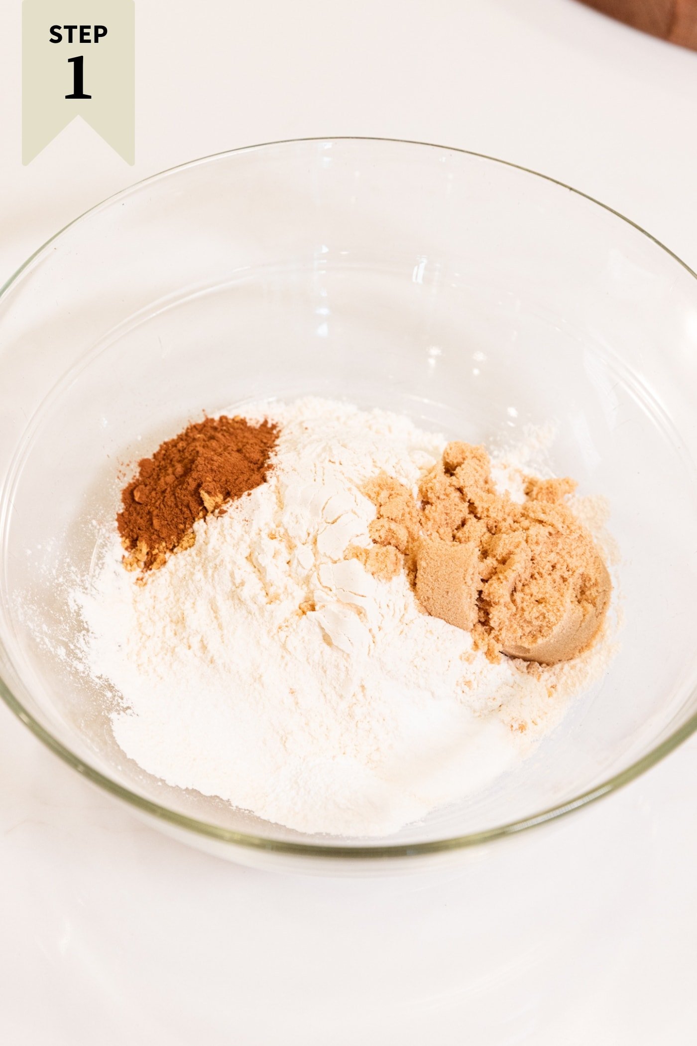 Glass bowl filled with flour, sugar, brown sugar, and spices before being mixed together.