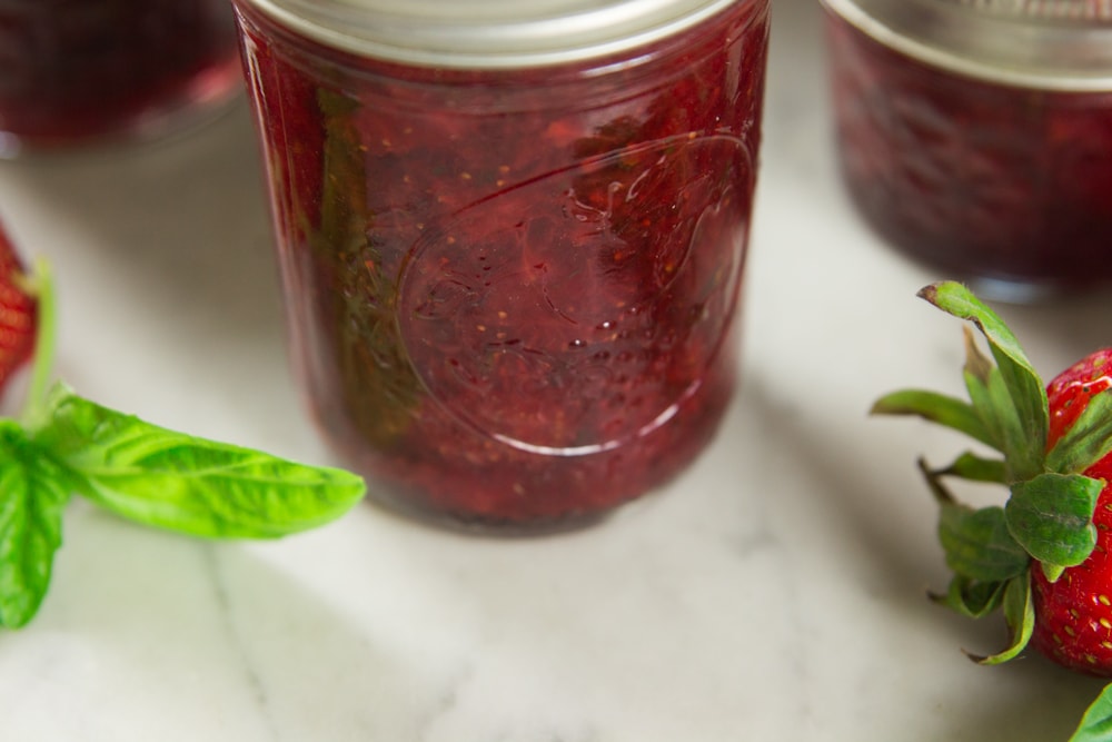 A jar full of strawberry basil preserves on a table.