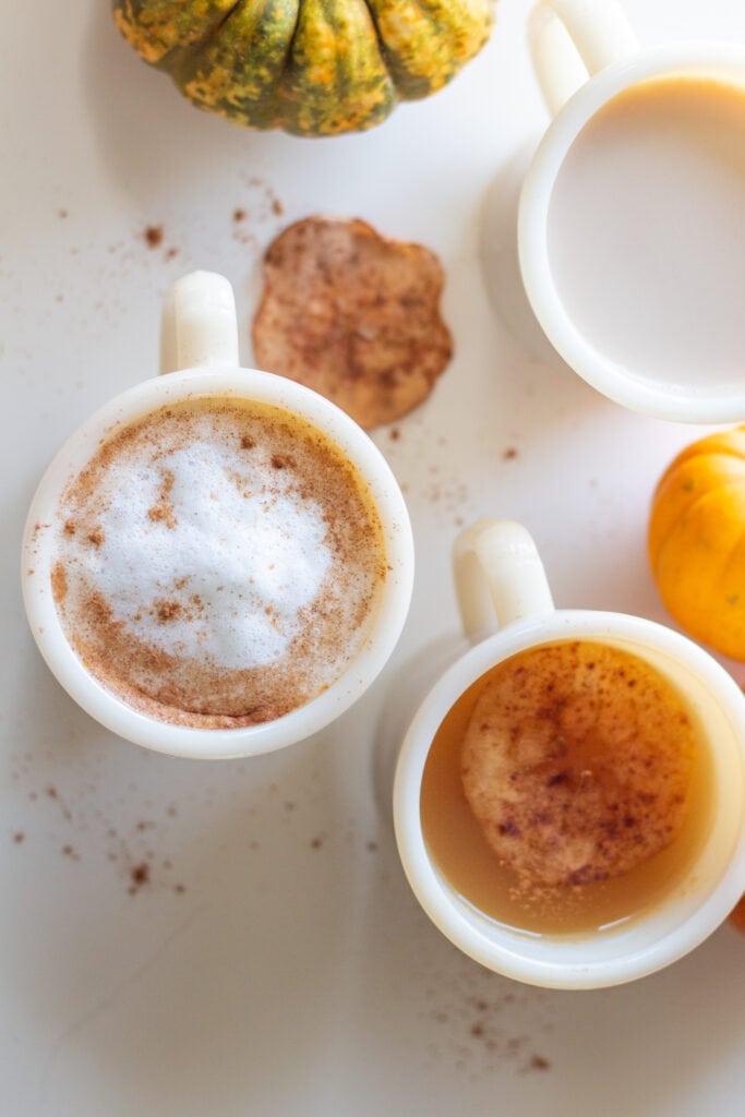 Mugs full of various flavored drinks sit on a table.