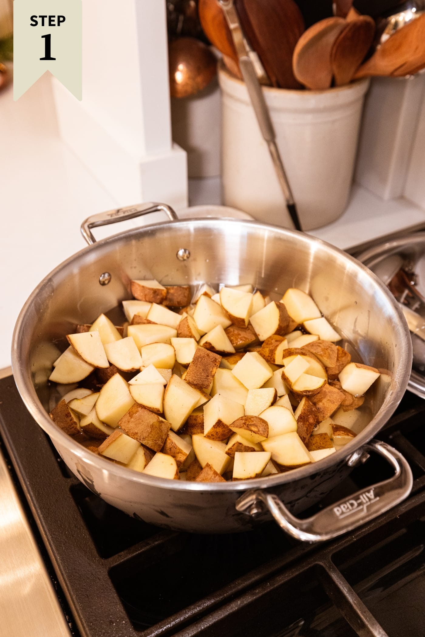 Large stockpot sitting on the stove with cubed pieces of raw potato.