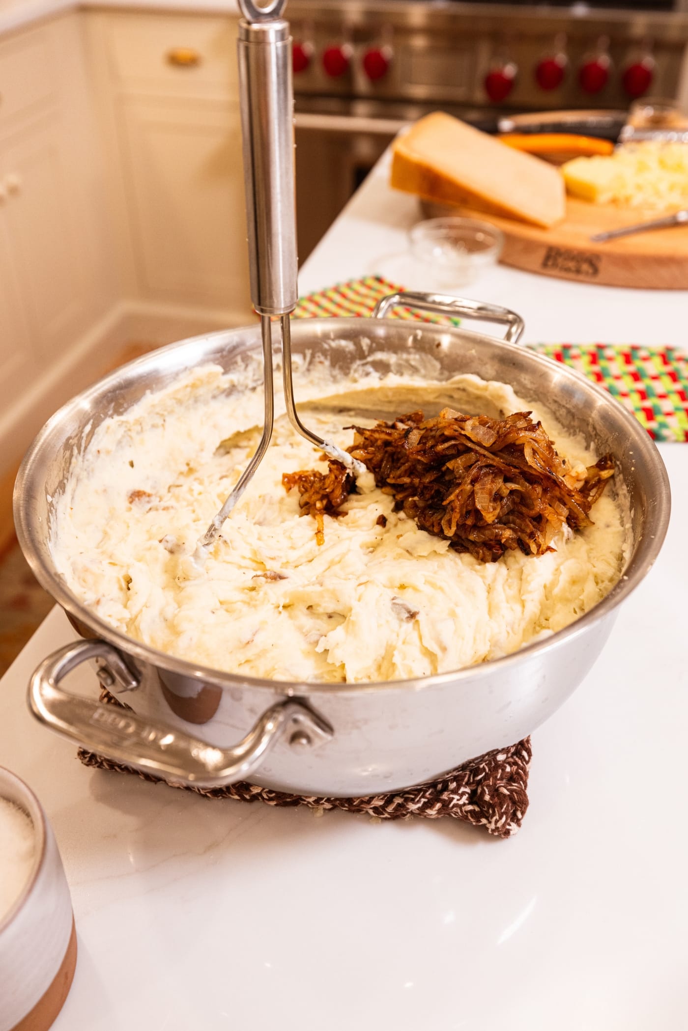 Large metal stockpot filled with mashed potatoes and caramelized onions before bing mixed together.