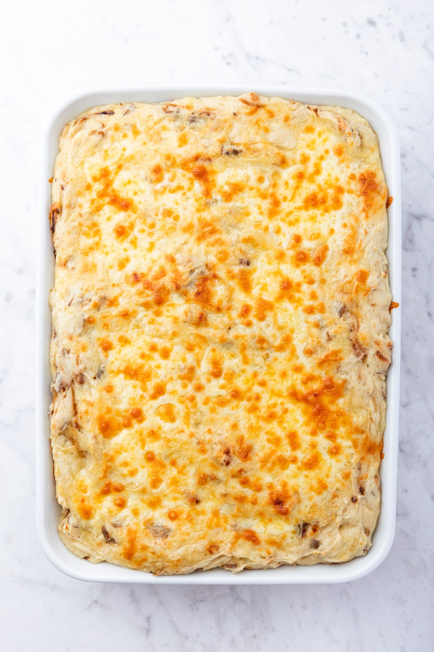 Large white baking dish filled with baked French onion potato casserole