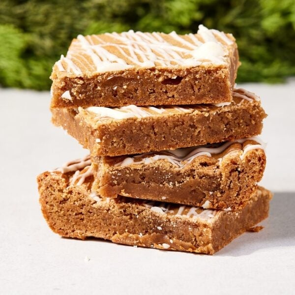 Stack of gingerbread blondies with melted white chocolate on top sitting in a stack showing dense interior texture.