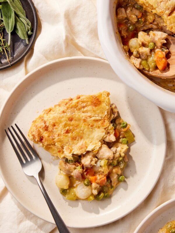 White plate filled with serving of chicken pot pie with fork resting to the side along with rest of pot pie.