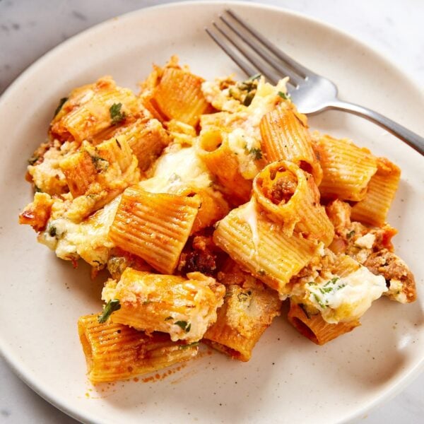 White plate filled with serving of lasagna casserole with fork resting on plate as well.