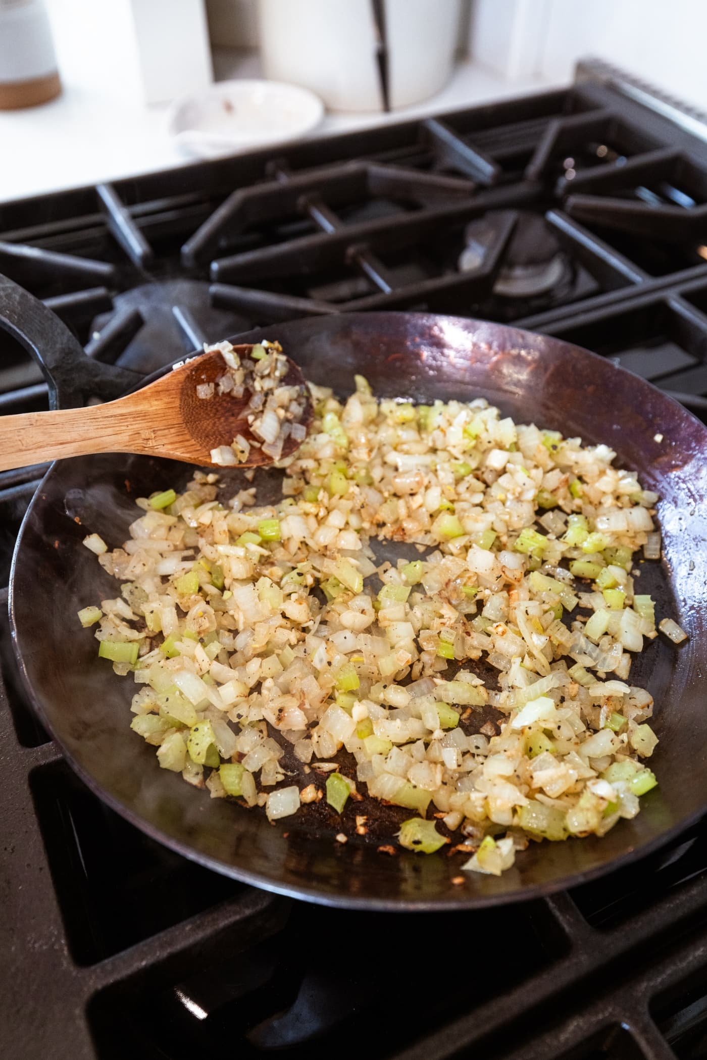 Browned mixture of celery and onion in a black skillet on the stovetop.