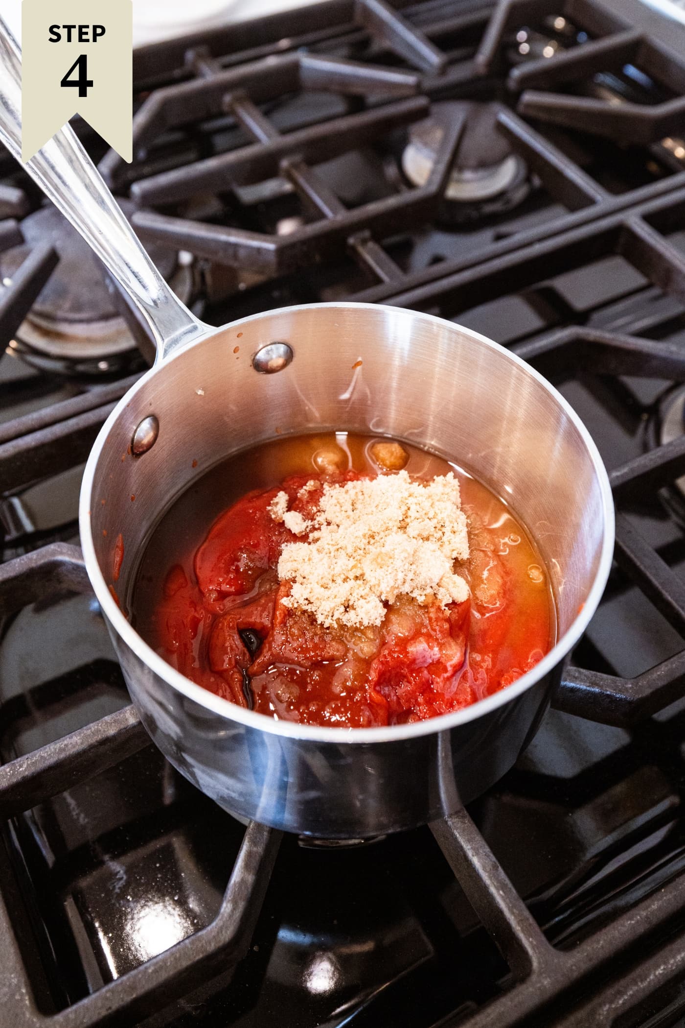 Small metal saucepan filled with ketchup, brown sugar, and more ingredients needed for a sauce to go over meatloaf meatballs.