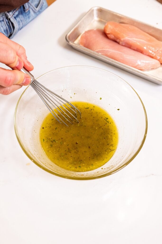 Glass bowl on white surface filled with ingredients needed for a marinade for chicken.