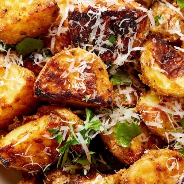 Crispy rosemary roasted potatoes topped with shredded cheese and fresh herbs right after coming out of the oven.
