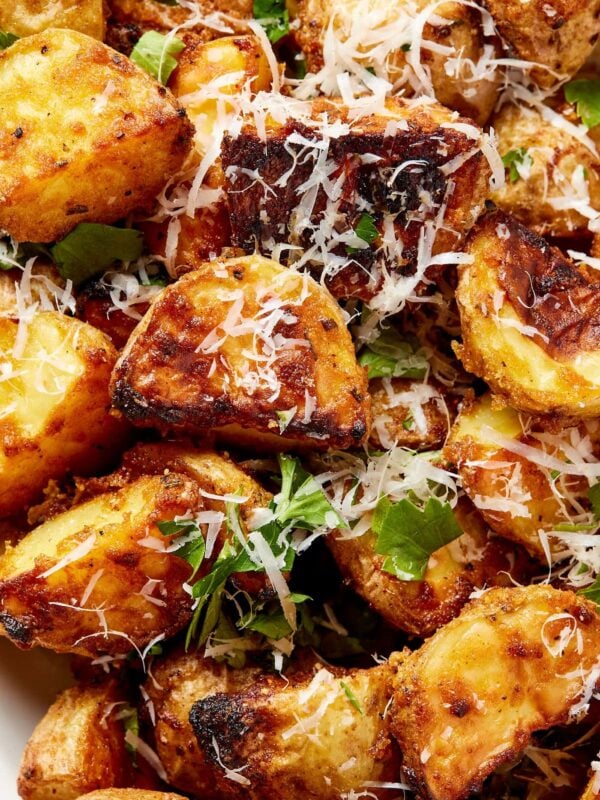 Crispy rosemary roasted potatoes topped with shredded cheese and fresh herbs right after coming out of the oven.