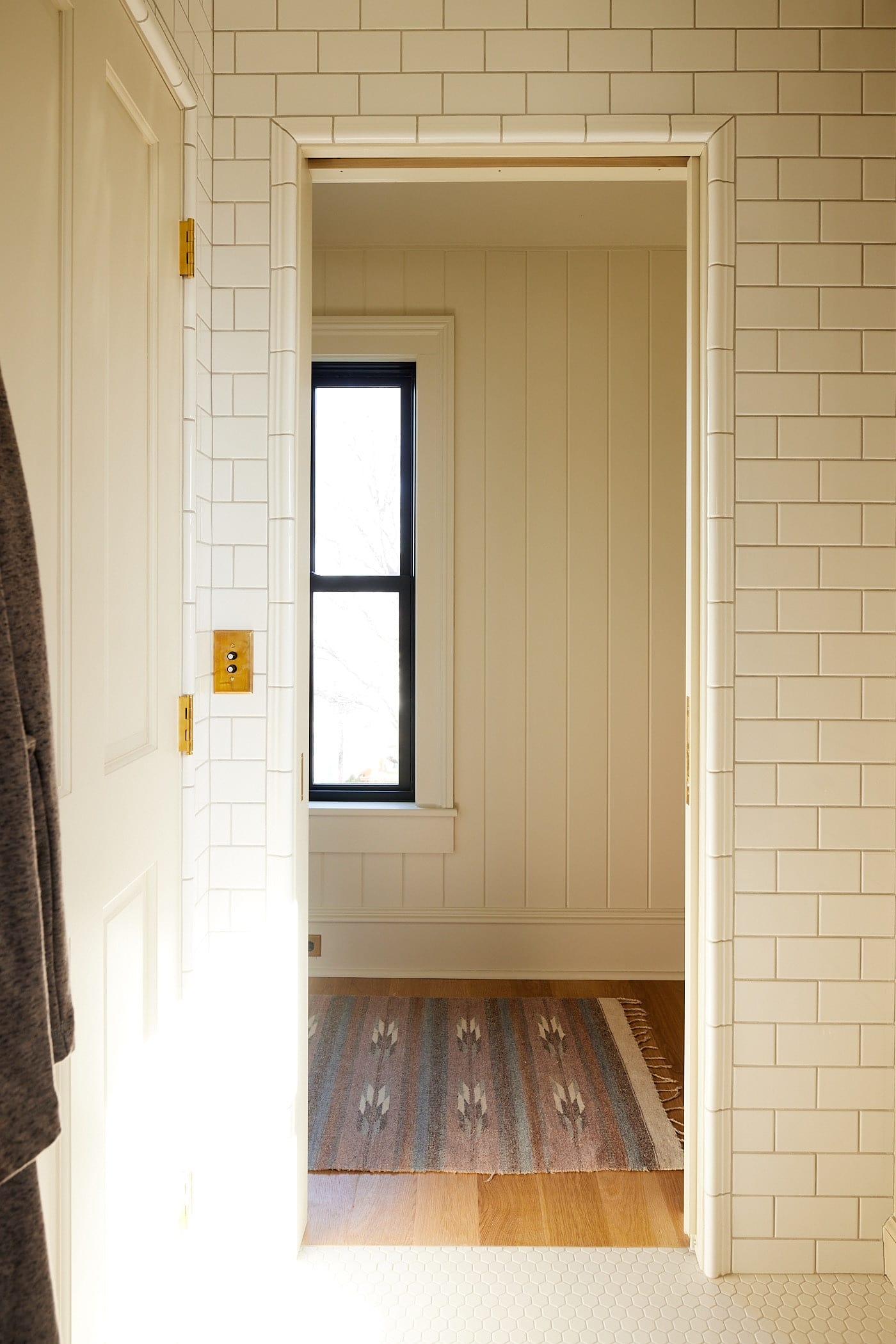 Open doorway into a bathroom with tile molding around the doorway with another door to the left side.