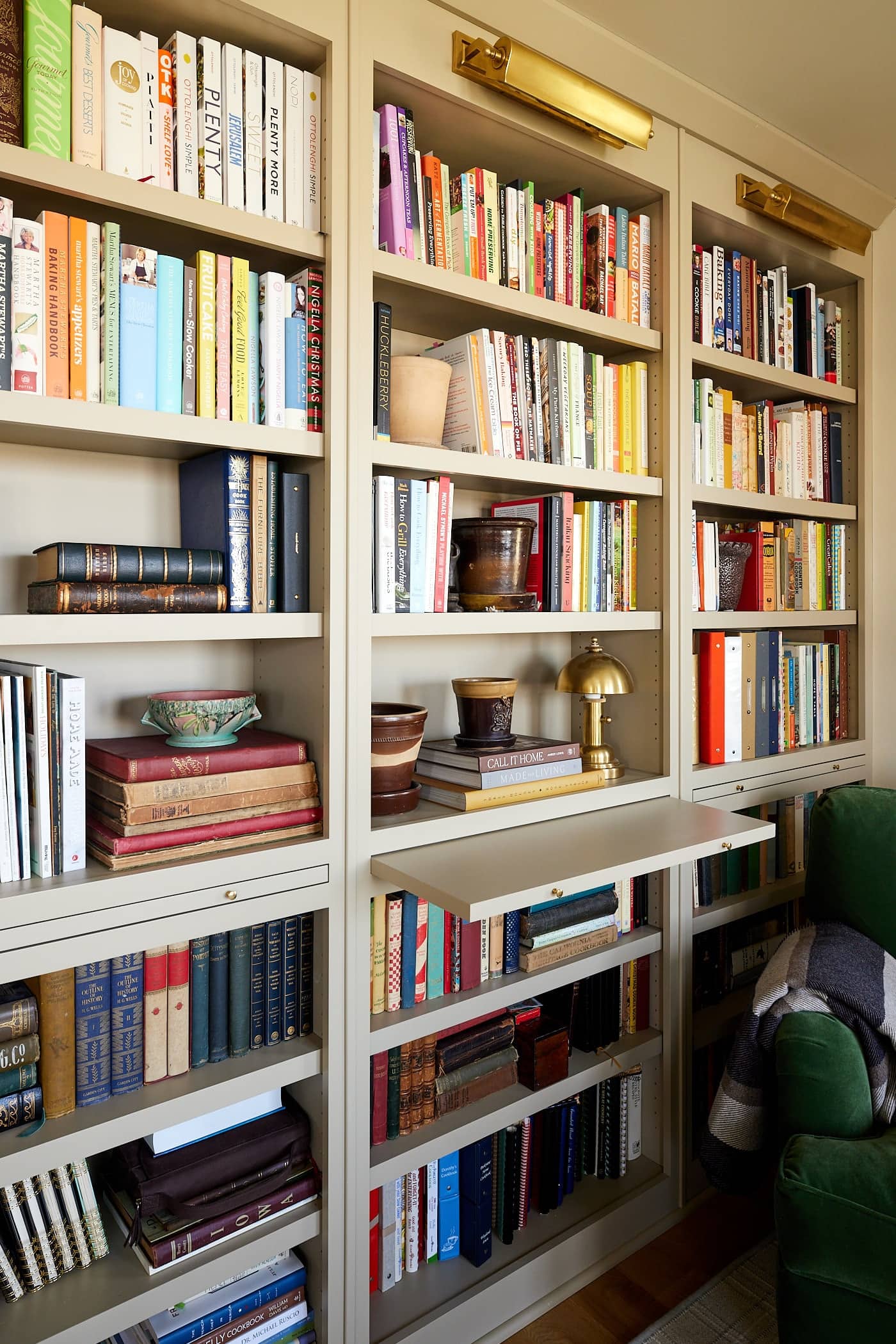 Bookcases filled with cookbooks with one pull-out shelf to set books on while browsing.