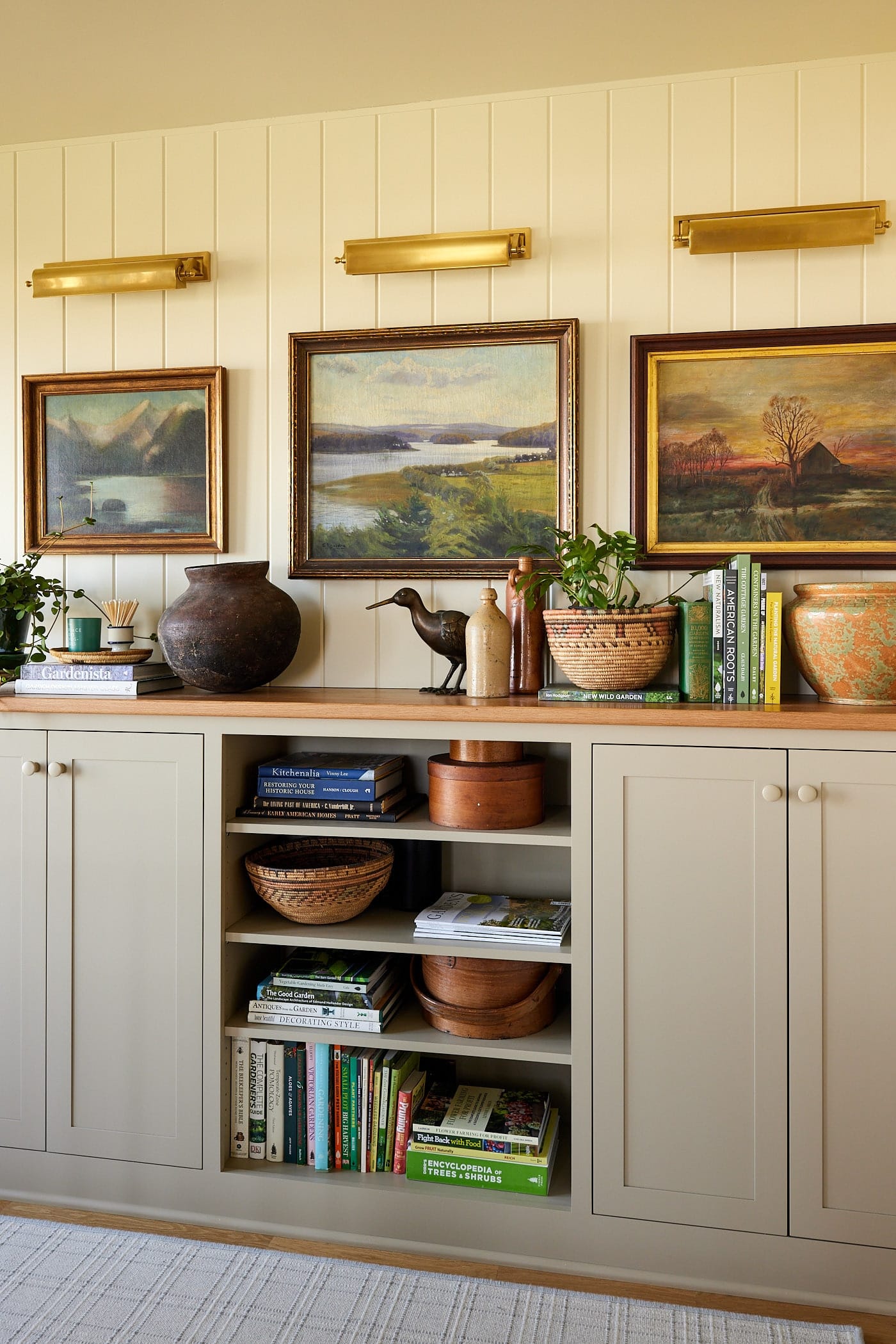 Built-in storage spaces with bookcase in between with display pieces and artwork on top framed with sconces on top.