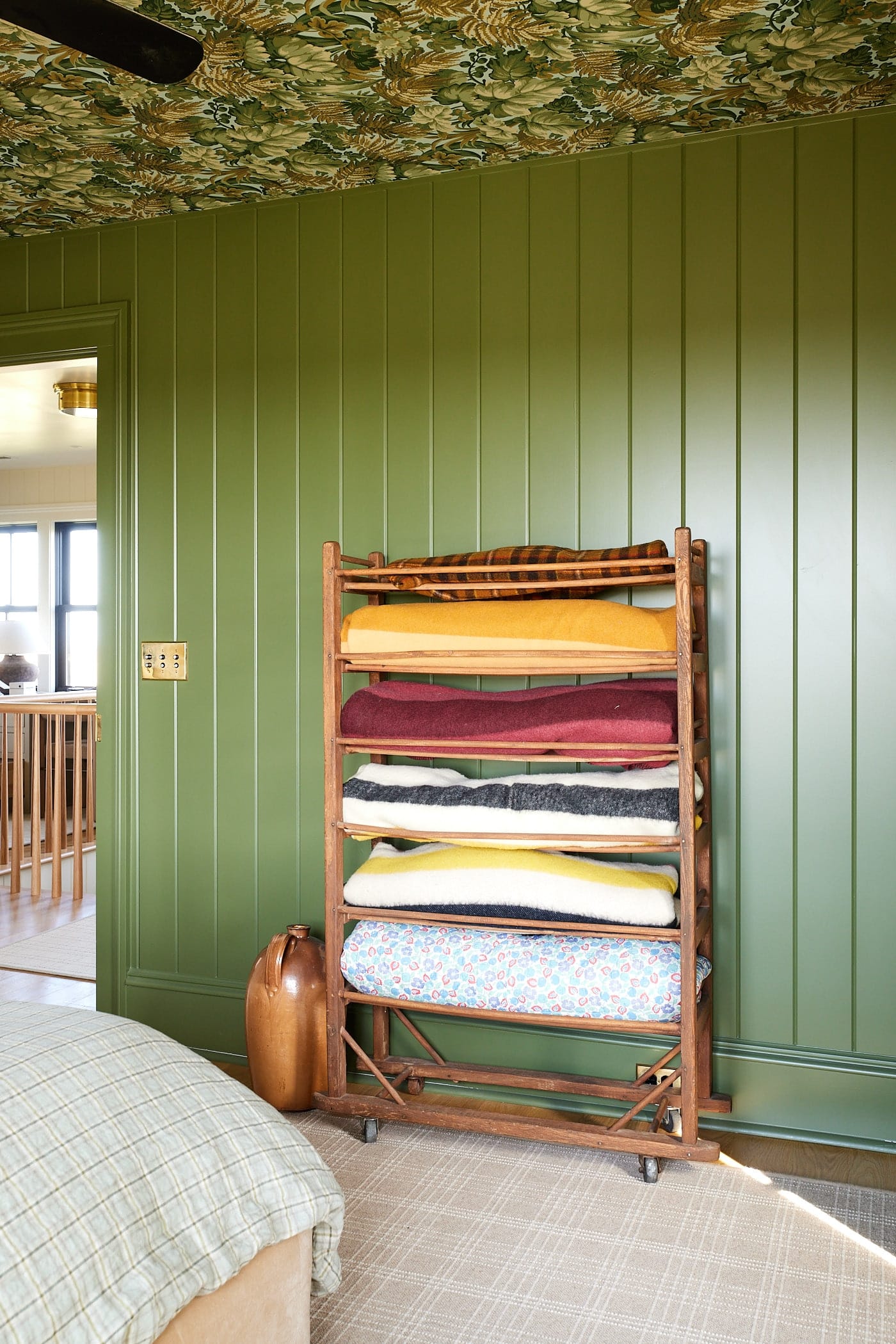 Bright green colored walls with tongue and groove walls with blanket shelf with brightly colored blankets.
