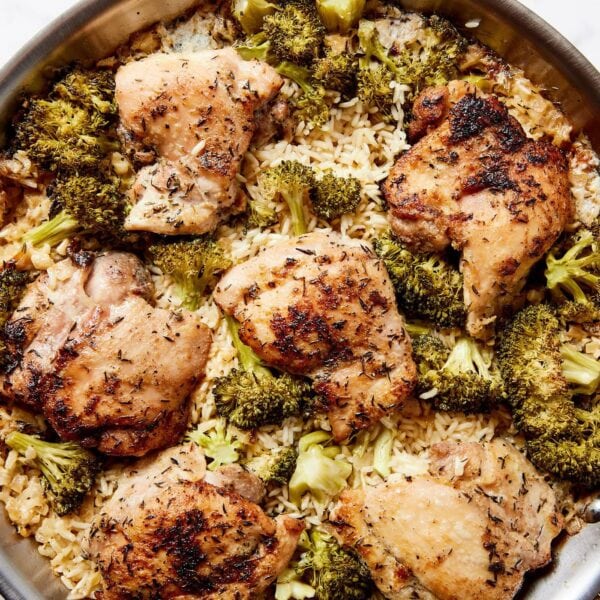 White marble surface with metal skillet with chicken, broccoli, and rice casserole inside.