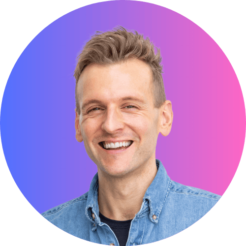 Kaleb Wyse wearing denim shirt standing in front of a blue to purple ombre background smiling.