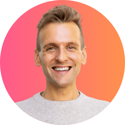 Kaleb Wyse standing in front of ombre pink to orange background wearing taupe sweater.