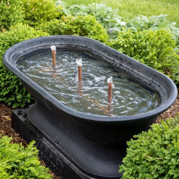 Black cast iron water fountain with copper bubblers with boxwood all around.