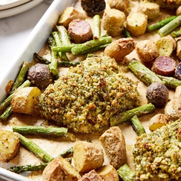 Sheet pan with herb crusted baked halibut with roasted potatoes and asparagus on sheet pan as well.