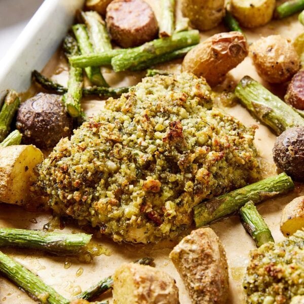 Piece of herb crusted halibut with roasted potatoes and asparagus also on sheet pan.