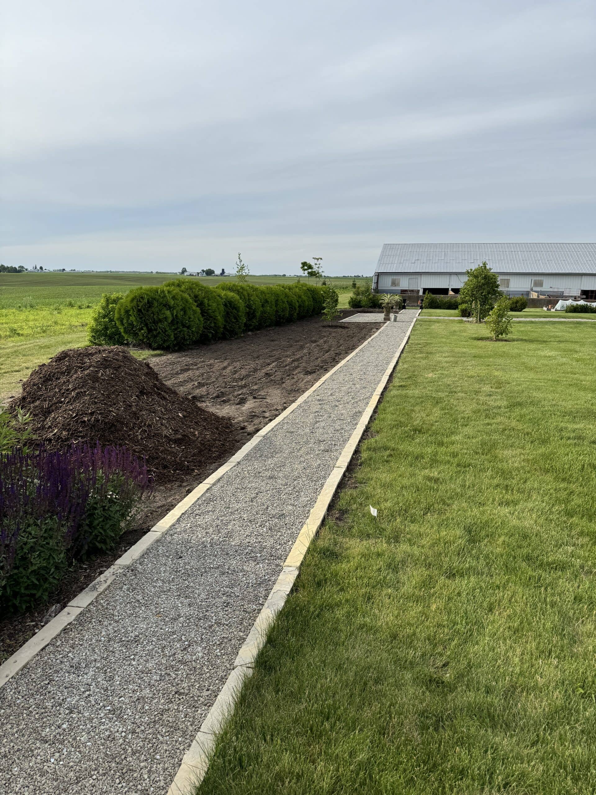 Gravel pathway edged with limestone pavers leading to a garden.